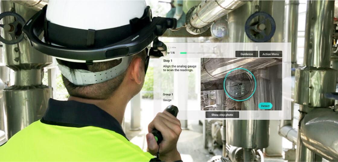 A_man_wearing_industrial_smart_glasses_uses_a_flashlight_to_inspect_factory_equipment_hands-free